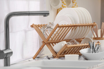 Sink and drying rack with clean dishes and cutlery on countertop in kitchen - obrazy, fototapety, plakaty