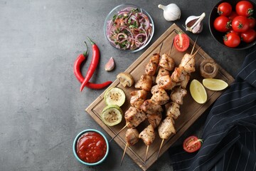 Delicious shish kebabs with sauce served on grey table, flat lay. Space for text