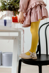Christmas decoration. Legs of a girl in yellow tights. Girl takes a gift