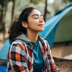 Fototapeta premium girl camping in the forest while closing her eyes and breathing the fresh air, vacation concept, nature, relaxation
