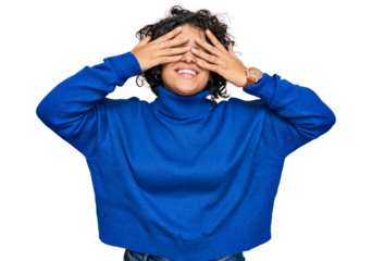 Young hispanic woman with curly hair wearing turtleneck sweater covering eyes with hands smiling cheerful and funny. blind concept.
