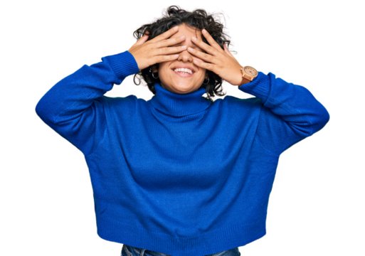 Young hispanic woman with curly hair wearing turtleneck sweater covering eyes with hands smiling cheerful and funny. blind concept. - Powered by Adobe