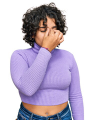 Young hispanic woman with curly hair wearing casual clothes tired rubbing nose and eyes feeling fatigue and headache. stress and frustration concept.