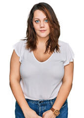 Young plus size woman wearing casual white t shirt relaxed with serious expression on face. simple and natural looking at the camera.