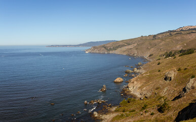 West California coast line, hills with grass and rocky reefs in Pacific ocean in Usa, America