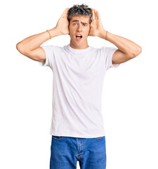 Young handsome man wearing casual white tshirt smiling cheerful playing peek a boo with hands showing face. surprised and exited