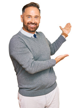 Handsome middle age man wearing business clothes inviting to enter smiling natural with open hand