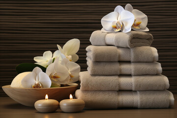 Fototapeta na wymiar Soothing Spa Scene. Accessories, Candles, Towels and Essential Oils for Relaxation and Rejuvenation. White orchid flowers decoration.