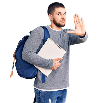 Young handsome man wearing student backpack holding notebook with open hand doing stop sign with serious and confident expression, defense gesture
