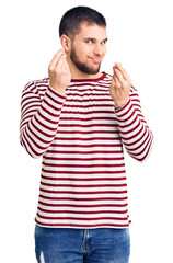 Naklejka premium Young handsome man wearing striped sweater doing money gesture with hands, asking for salary payment, millionaire business