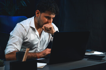 Stressful businessman using laptop to analyze database information of marketing planer, sending...