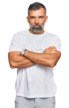 Middle age handsome man wearing casual white tshirt skeptic and nervous, disapproving expression on face with crossed arms. negative person.