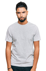 Young man with beard wearing casual grey tshirt skeptic and nervous, frowning upset because of...