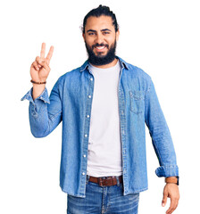 Young arab man wearing casual denim shirt smiling with happy face winking at the camera doing victory sign. number two.