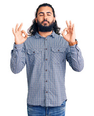Young arab man wearing casual clothes relaxed and smiling with eyes closed doing meditation gesture with fingers. yoga concept.
