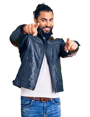 Fototapeta premium Young arab man wearing casual leather jacket pointing to you and the camera with fingers, smiling positive and cheerful