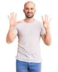 Young handsome man wearing casual t shirt showing and pointing up with fingers number nine while smiling confident and happy.