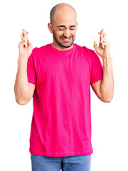 Fototapeta premium Young handsome man wearing casual t shirt gesturing finger crossed smiling with hope and eyes closed. luck and superstitious concept.