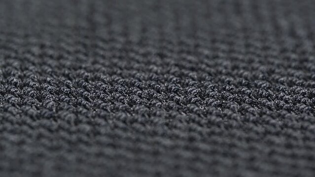 texture of the knitted textured boucle fabric is dark gray. close-up rotation, macro. cozy stylish fabric background of textile production.
