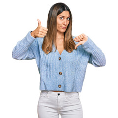 Young woman wearing casual clothes doing thumbs up and down, disagreement and agreement expression. crazy conflict