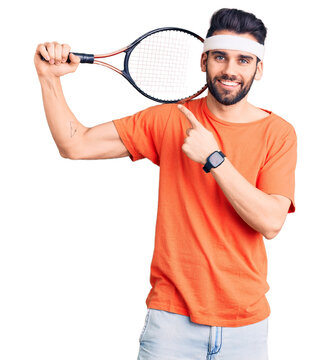 Young handsome man with beard playing tennis holding racket smiling happy pointing with hand and finger