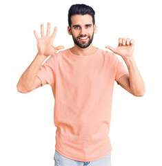 Naklejka premium Young handsome man with beard wearing casual t-shirt showing and pointing up with fingers number six while smiling confident and happy.