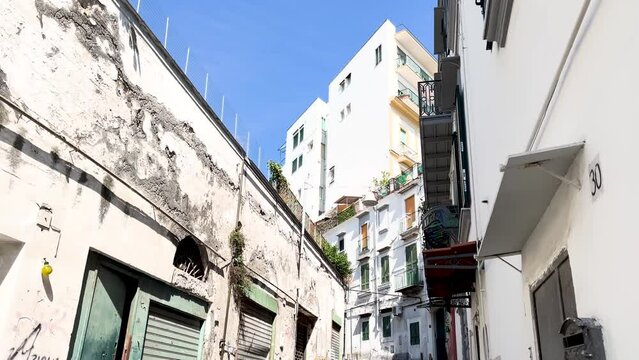 Quiet, narrow alley with closed shops and graffiti, daytime - Neapol, Italy