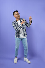 Portrait of a young Asian man points away on copy space, discusses amazing promo, gives direction, and isolated on a purple background.