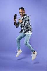 Portrait of a young man with empty smartphones jumping up in the air, wearing a shirt and isolated...