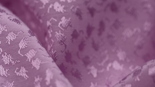 slow rotation of folds of plain jacquard fabric of lilac color in closeup. macro texture of the factory material with a woven pattern. textured abstract ornament of a textile background.