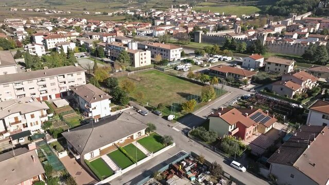Soave Comune Residential Houses, Football Pitch, And Campers RV Park Near Scaliger Walls In Italy. - aerial shot