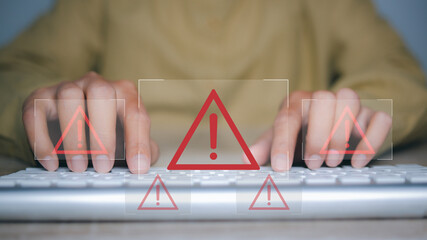 Man using laptop with triangle caution warning sign for notification error.
