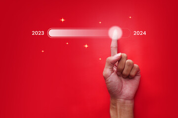 Businessman's hand touches the year-end download status bar to change from 2023 to 2024. ...