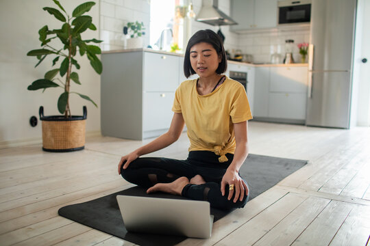 Woman practicing yoga with laptop online class at home