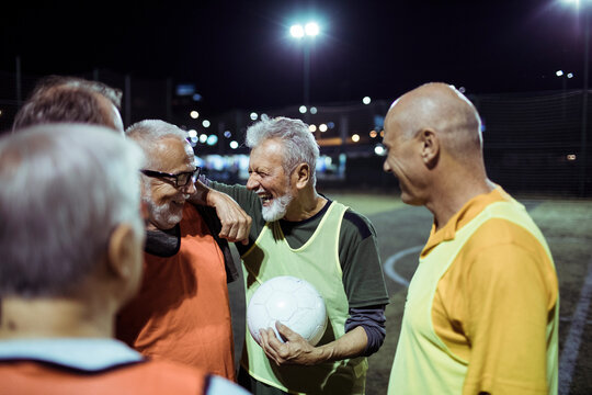 Happy senior men talking on soccer field