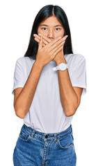 Beautiful young asian woman wearing casual white t shirt shocked covering mouth with hands for mistake. secret concept.