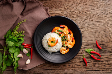 Stir-fried shrimp with basil and eggs Thai street food arranged on black plates Spicy Thai food placed on a wooden table. Top view.