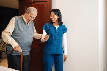 Nurse helping to walk to an old man at home