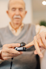 Elder man use fingertip pulse oximeter check blood oxygen pressure