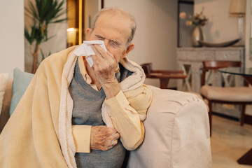 Senior man sick with flu blowing nose