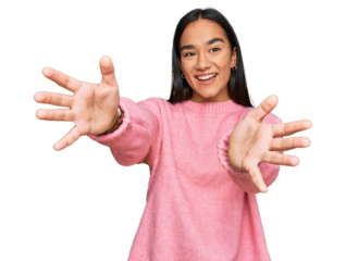 Young asian woman wearing casual winter sweater looking at the camera smiling with open arms for hug. cheerful expression embracing happiness.