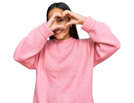 Young asian woman wearing casual winter sweater doing heart shape with hand and fingers smiling looking through sign - Powered by Adobe