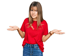 Teenager caucasian girl wearing casual red t shirt clueless and confused with open arms, no idea...
