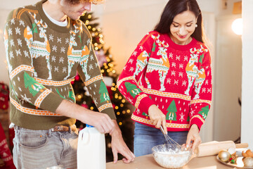 Young couple lover enjoy making desserts to celebrate Christmas. Inside the house. Man and woman are having fun food cooking on the celebration day.