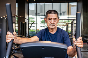 Asian old man in the 70s or 80s to step on flywheel training helping leg muscle strength, Healthy...