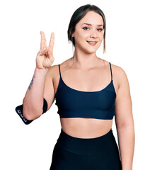 Young hispanic woman wearing sportswear showing and pointing up with fingers number three while smiling confident and happy.