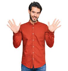 Fototapeta premium Young hispanic man wearing casual clothes showing and pointing up with fingers number ten while smiling confident and happy.
