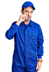 Middle age handsome man wearing mechanic uniform mouth and lips shut as zip with fingers. secret and silent, taboo talking