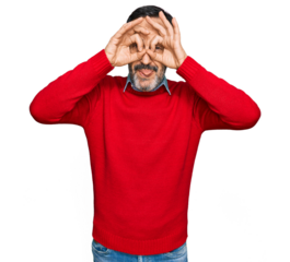 Middle age hispanic man wearing casual clothes doing ok gesture like binoculars sticking tongue out, eyes looking through fingers. crazy expression.