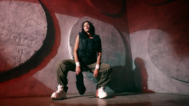 female gangster rapper in bulletproof vest and military clothing dancing in studio, portrait shot